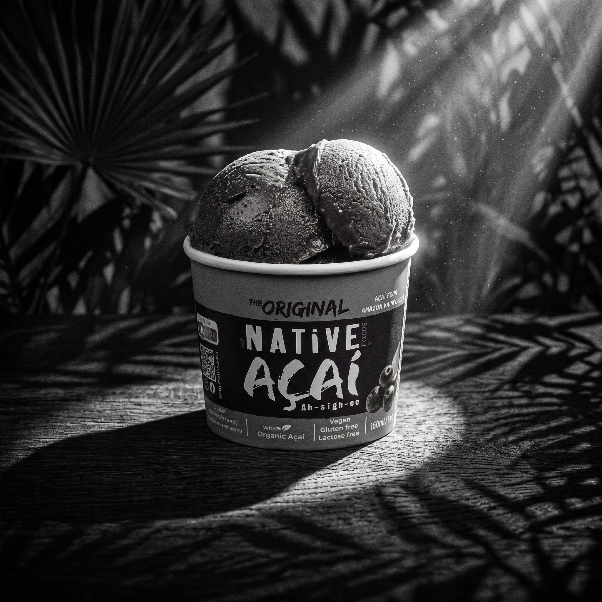 Copo de gelado com duas bolas e rótulo "The Original Native Açaí", sobre madeira com sombras de palmeiras